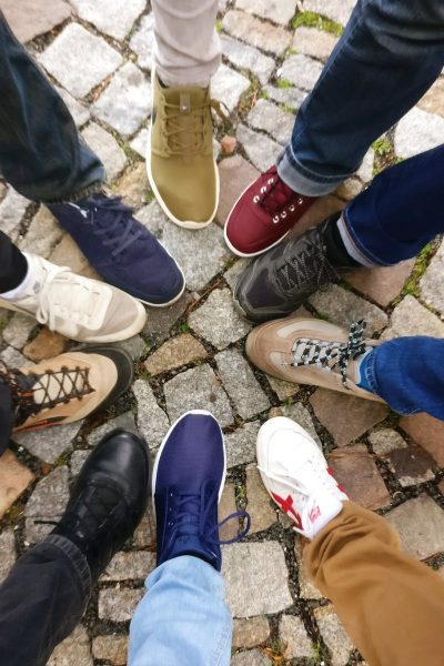 Circle of sneakers on cobblestone pavement representing diversity and urban fashion.